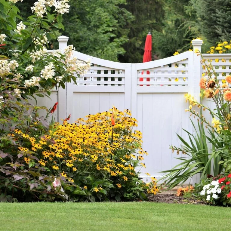 colorful flower garden against a white fence